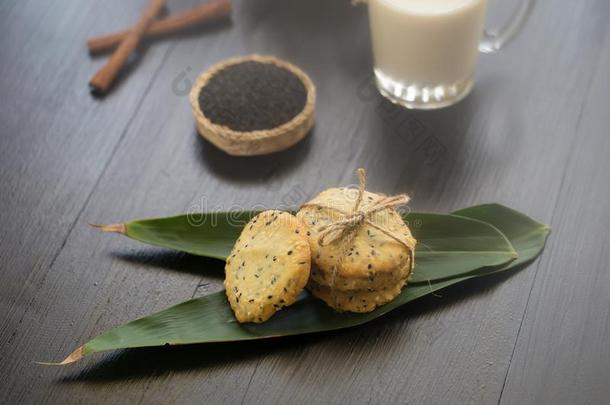 芝麻甜饼干,芝麻和奶向黑的木制的背景