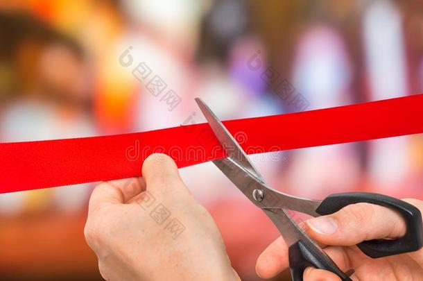 手和剪刀锋利的红色的带-开幕典礼