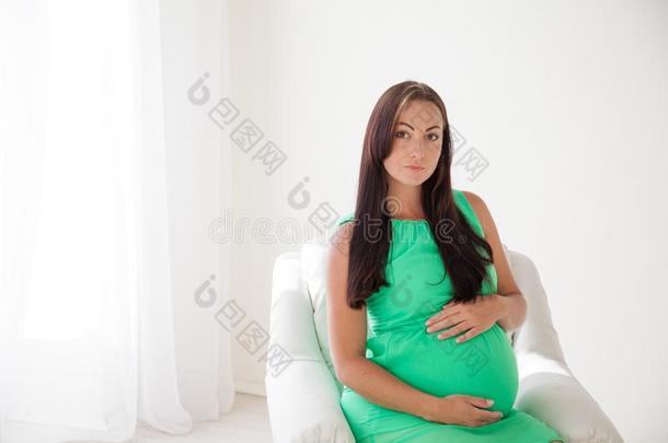 一怀孕的女人在之前分娩坐采用白色的长沙发椅