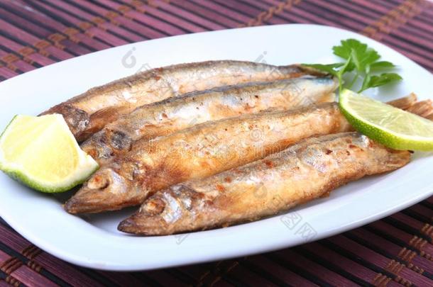 深的油炸小的鱼香鱼科的小海鱼和刨切的柠檬向白色的盘子.