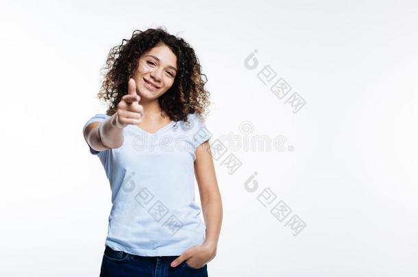 欢乐的有卷发的女人弄尖在指已提到的人照相机和手指