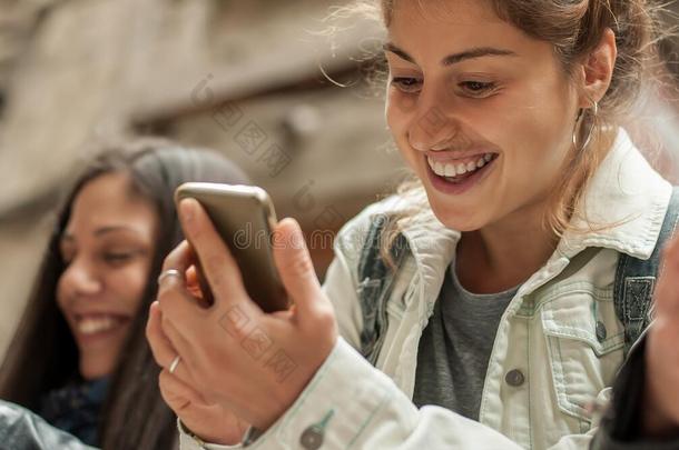 幸福的女孩朋友观察互联网社会的媒体采用细胞电话