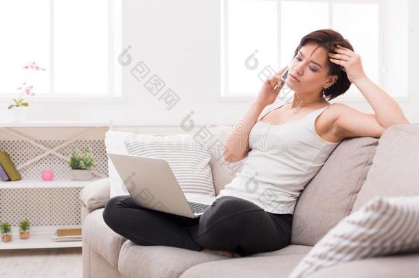 沉思的女孩和便携式电脑和可移动的一次向米黄色长沙发椅