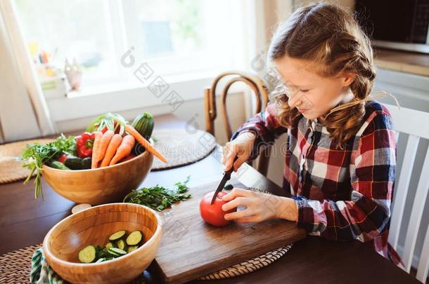 小孩女孩助手妈妈向烹调和将切开新鲜的蔬菜为沙拉