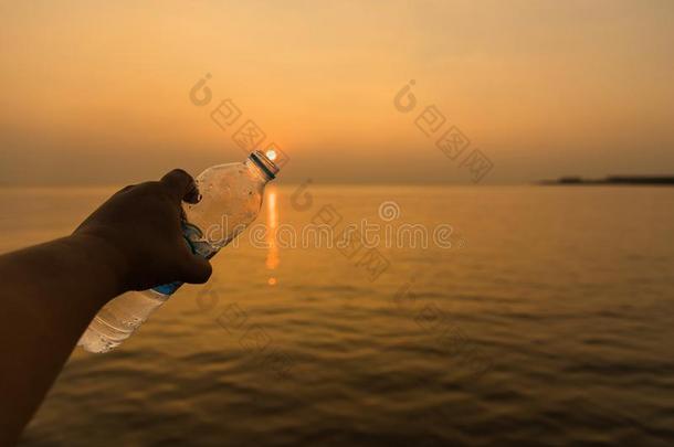 男人手佃户租种的土地喝饮料水瓶子在金色的小时日落用绳子拖的平底渡船