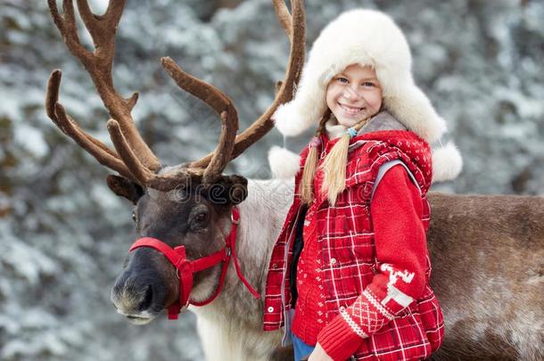 冬游戏时间.幸福的小的女孩热烈地拥抱她驯鹿.
