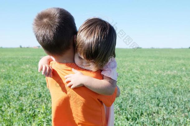小的女孩热烈地拥抱男孩,幸福的兄弟童年