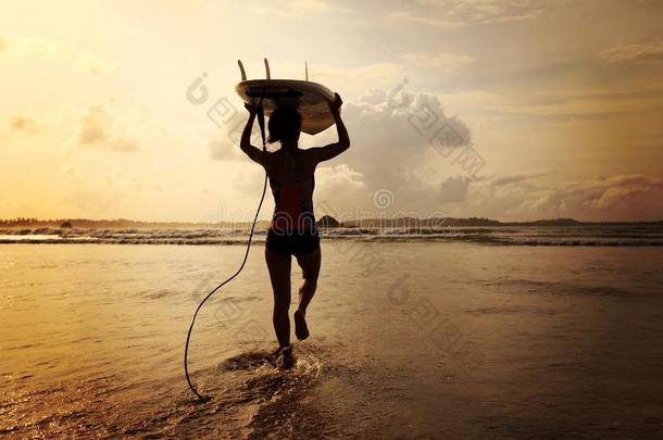 女人冲浪运动员和白色的冲浪板步行向指已提到的人海