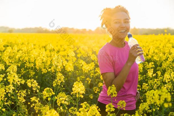 混合的赛跑非洲的美国人女孩十几岁的青少年喝饮料水日落