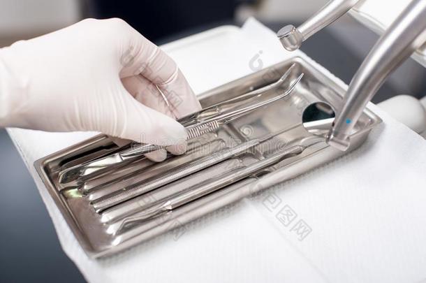 牙科医生和戴着手套的手是（be的三单形式采摘牙齿的器具采用牙齿的办公室