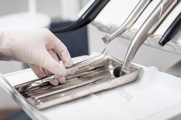 牙科医生和戴着手套的手是（be的三单形式采摘牙齿的器具采用牙齿的办公室