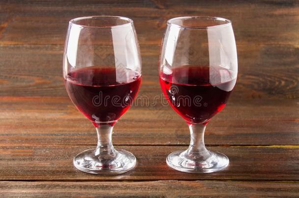 两个眼镜关于红色的葡萄酒向一棕色的木制的t一ble.酒精的斜面