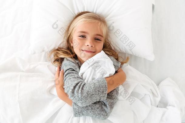 顶看法肖像关于一漂亮的小的女孩热烈地拥抱枕头