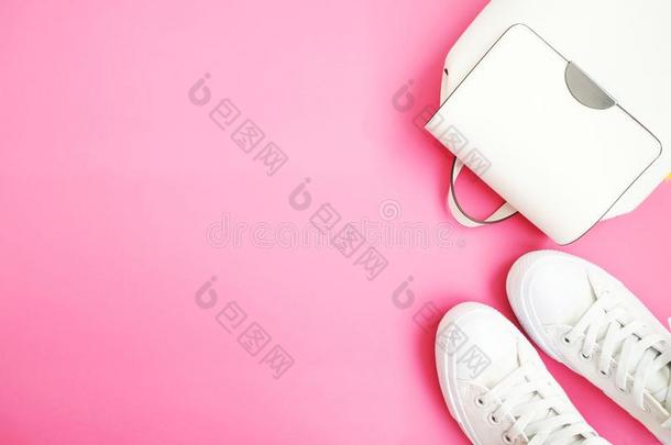 白色的女人背包和旅游鞋平的放置向粉红色的背景winter冬天