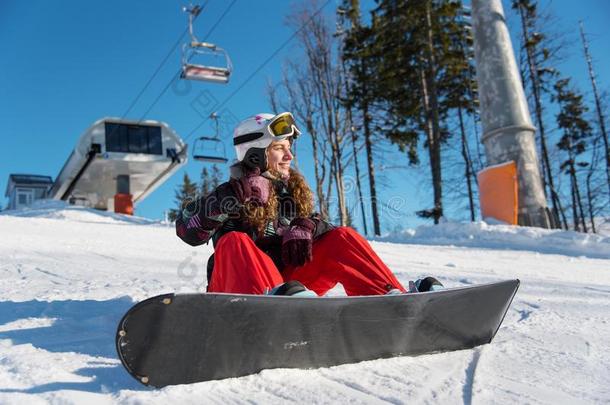 微笑的女孩和滑雪板坐向雪采用太阳微量