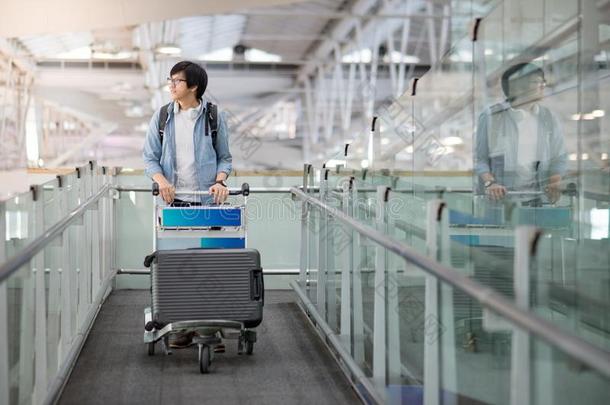 年幼的亚洲人男人步行和手推车采用机场term采用al