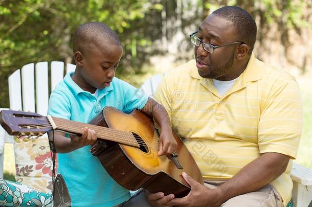 父亲教学他的他的儿子向比赛指已提到的人吉他.