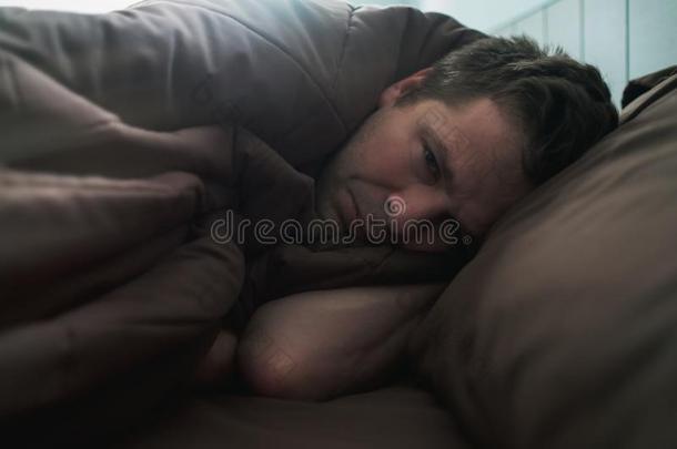 触怒高加索人男人躺向床和遮盖他自己和毛毯