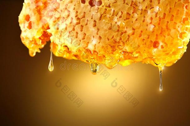 蜂蜜滴从蜂蜜梳子向黄色的背景