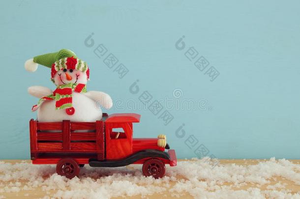 影像关于雪人向指已提到的人木制的老的玩具汽车越过下雪的木制的帐单