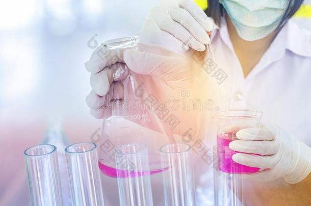 科学家女人滴下粉红色的化学的液体和试验管巨大左心房