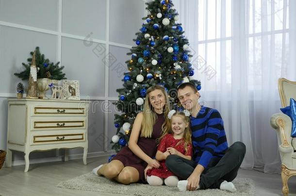 幸福的家庭在近处圣诞节树.幸福的妈妈爸爸和女儿热烈地拥抱
