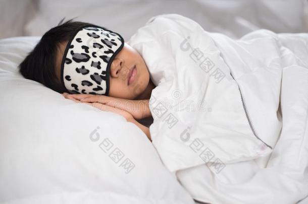 男孩睡眠向床白色的枕头和纸和睡面具