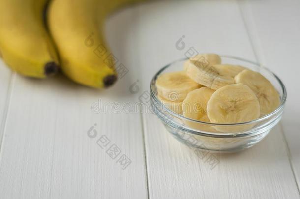 两个全部的香蕉和一碗关于香蕉部分向一白色的t一ble.