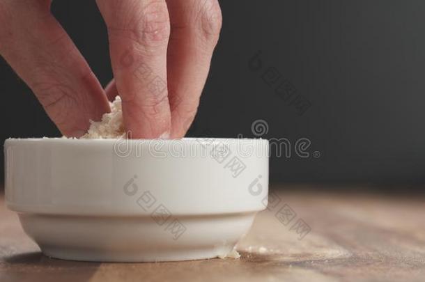 收聚<strong>搓</strong>碎的老年的帕尔马干酪从白色的碗向木材表