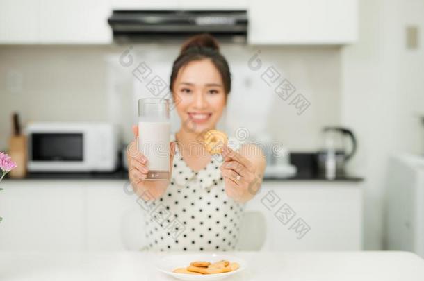年幼的亚洲人女人佃户租种的土地奶玻璃咬饼干采用她厨房
