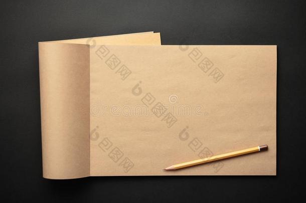 牛皮纸笔记簿和铅笔向黑的背景,手艺笔记给装衬垫