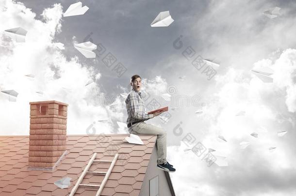 男人向砖屋顶<strong>阅读</strong>书和纸位面飞行的采用天空