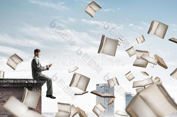 男人使用智能手机和许多书飞行的采用天空