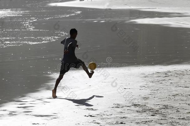 年幼的人演奏足球向指已提到的人海滩