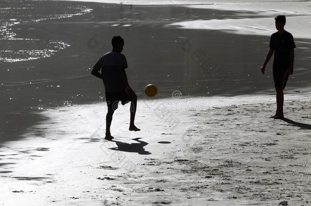 年幼的人演奏足球向指已提到的人海滩