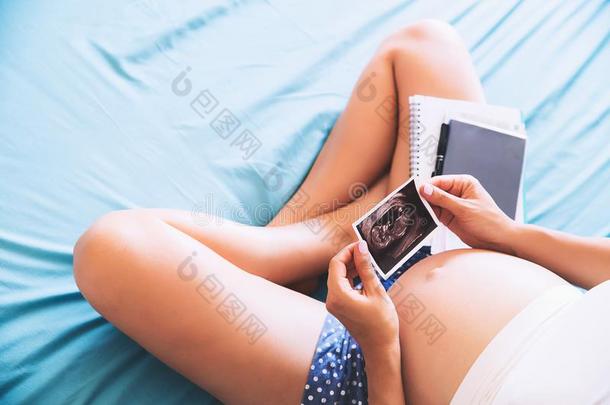 怀孕的女人使记下采用笔记簿和hold采用g超声image形象