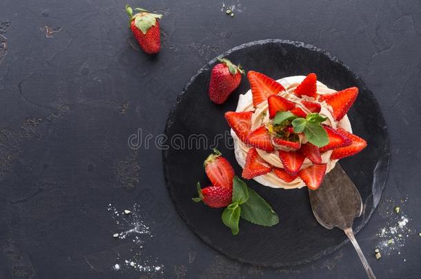 安娜奶油水果蛋白饼蛋糕和草莓向黑的背景