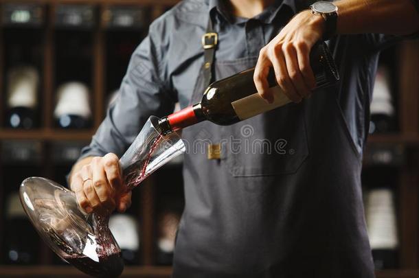 酒吧间销售酒精饮料的人涌出红色的葡萄酒采用透明的容器采用地下室