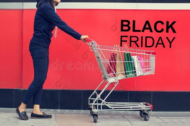 黑的星期五,女人顾客和购物袋采用一手推车