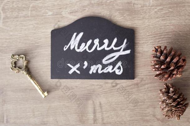 愉快的圣诞节文本符号和松树圆锥体和钥匙装饰