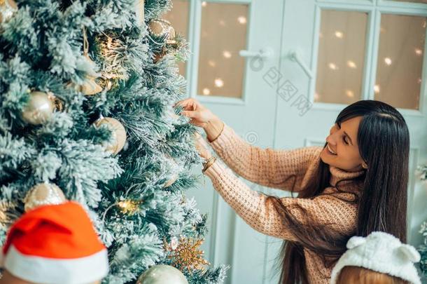 漂亮的女孩和她mot她装饰枞树向圣诞节前夕