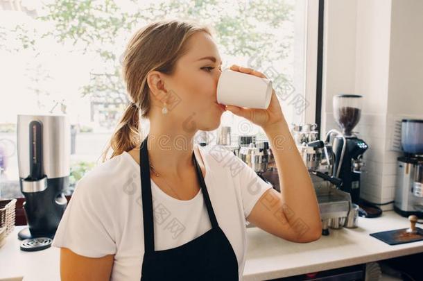 年幼的高加索人女人咖啡馆准备咖啡的员工喝饮料从纸杯子.