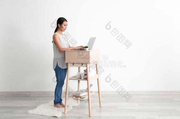 亚洲人女人打字向便携式电脑在台-在上面工作场所