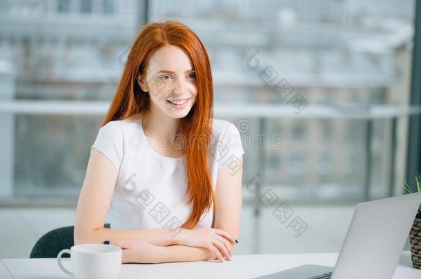 美丽的红发的人女孩工厂在便携式电脑和有样子的在照相机