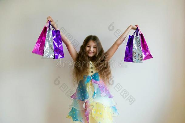 时尚微笑的小的女孩和购物袋和礼物.