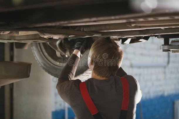 技工从旋出螺丝部关于汽车`英文字母表的第19个字母底部在下面举起Cana加拿大