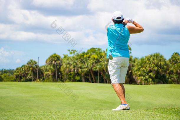 高尔夫球手打球向美丽的高尔夫球课程