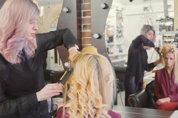 女人理发师制造一绺鬈发在亚麻色的头发和冰壶镣铐