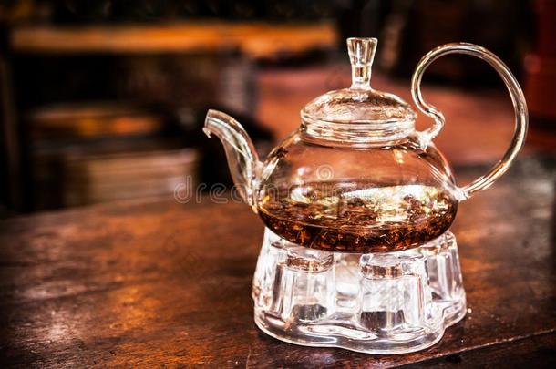 玻璃茶壶和茶水树叶向木制的表和黑暗的背景