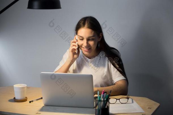 年幼的微笑的女人讲话可移动的电话和工作的采用even采用g